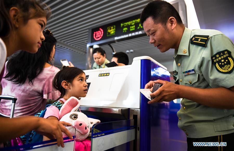 Wang Zhiguo (R) checks passengers\' identity certificates at Nanjing Lukou International Airport in Nanjing, capital of east China\'s Jiangsu Province, Aug. 7, 2018. Wang Jicai, who used to be head of the militia post on Kaishan Island in Jiangsu Province, started working on the island in the Yellow Sea with his wife in 1986. He died of sudden illness while on duty in July of 2018 at the age of 58. Wang Zhiguo, son of Wang Jicai, became a frontier defence policeman after his graduation from Nanjing University of Aeronautics and Astronautics in 2013. He had been assigned to many security tasks for major events during 5 years\' working. (Xinhua/Li Xiang)