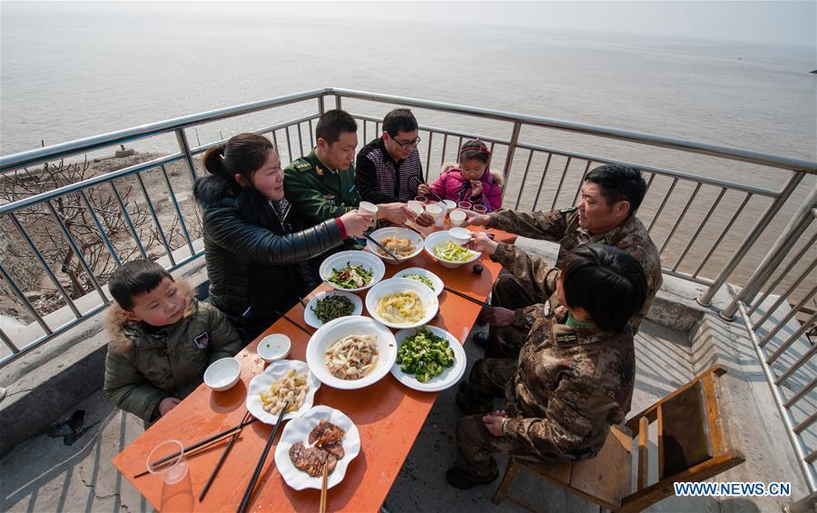 Wang Zhiguo (3rd L) enjoys dinner with family members on Kaishan Island of Guanyun County, east China\'s Jiangsu Province, Feb. 13, 2015. Wang Jicai, who used to be head of the militia post on Kaishan Island in Jiangsu Province, started working on the island in the Yellow Sea with his wife in 1986. He died of sudden illness while on duty in July of 2018 at the age of 58. Wang Zhiguo, son of Wang Jicai, became a frontier defence policeman after his graduation from Nanjing University of Aeronautics and Astronautics in 2013. He had been assigned to many security tasks for major events during 5 years\' working. (Xinhua/Li Xiang)