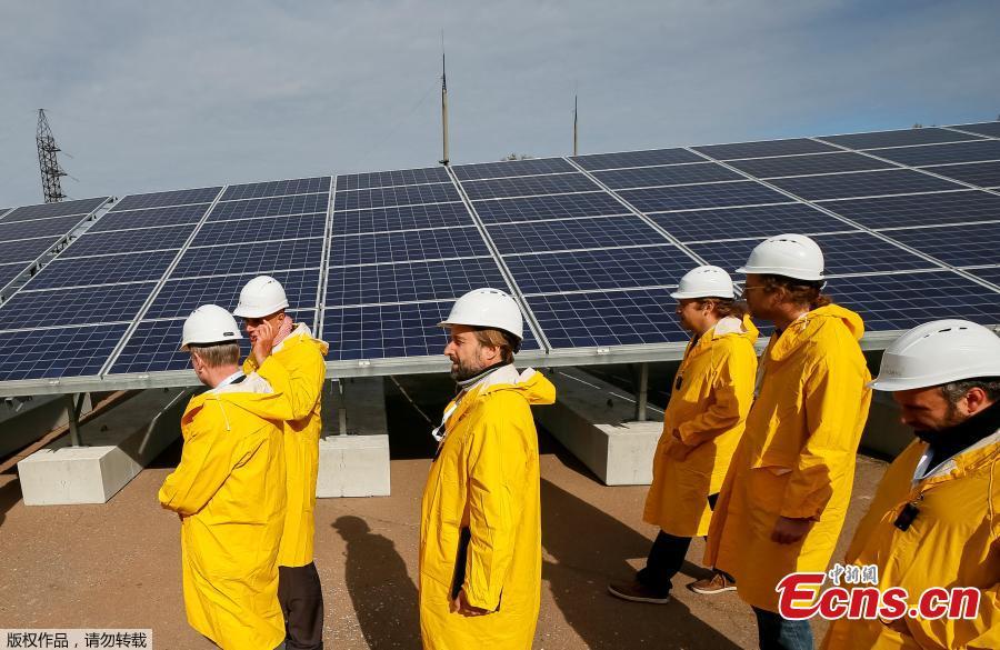Visitors walk by the photovoltaic panels during an official opening ceremony of the new one-megawatt solar power plant \'\'Solar Chernobyl\