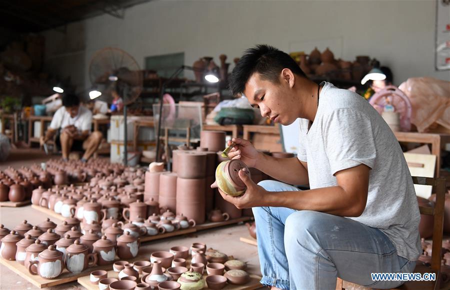 A staff member works on a Nixing pottery ware at a workshop in Qinzhou, south China\'s Guangxi Zhuang Autonomous Region, Oct. 9, 2018. The making of Nixing pottery is a well-preserved tradition in Qinzhou. In 2008, the techniques of making Nixing pottery were listed as one of China\'s state-level intangible cultural heritages. Currently, over 10,000 workers are engaged in the Nixing pottery industry in Qinzhou, producing more than 1,000 pottery varieties. (Xinhua/Lu Boan)