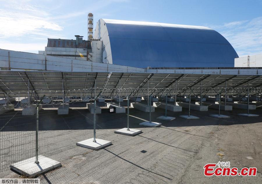 Visitors walk by the photovoltaic panels during an official opening ceremony of the new one-megawatt solar power plant \'\'Solar Chernobyl\