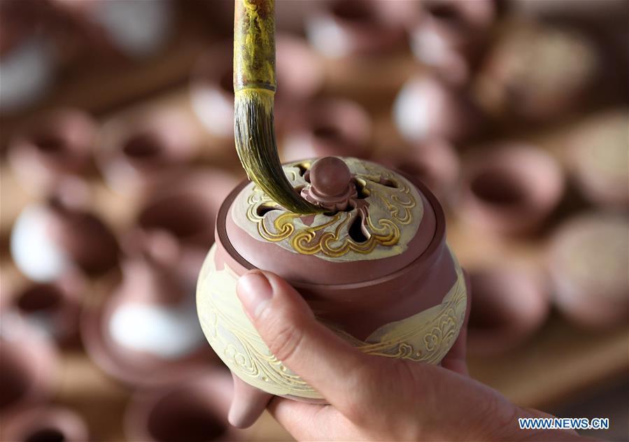 A staff member works on a Nixing pottery ware at a workshop in Qinzhou, south China\'s Guangxi Zhuang Autonomous Region, Oct. 9, 2018. The making of Nixing pottery is a well-preserved tradition in Qinzhou. In 2008, the techniques of making Nixing pottery were listed as one of China\'s state-level intangible cultural heritages. Currently, over 10,000 workers are engaged in the Nixing pottery industry in Qinzhou, producing more than 1,000 pottery varieties. (Xinhua/Lu Boan)