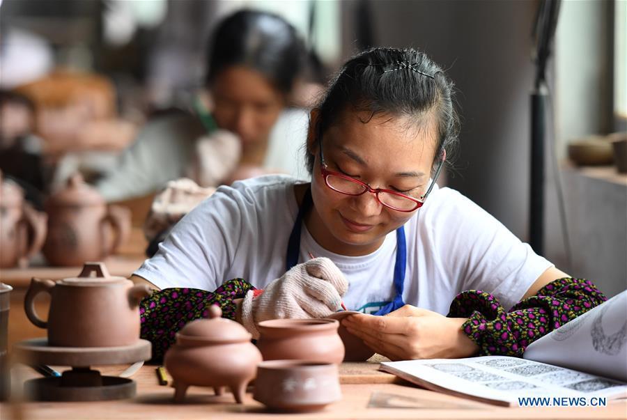 A staff member works on a Nixing pottery ware at a workshop in Qinzhou, south China\'s Guangxi Zhuang Autonomous Region, Oct. 9, 2018. The making of Nixing pottery is a well-preserved tradition in Qinzhou. In 2008, the techniques of making Nixing pottery were listed as one of China\'s state-level intangible cultural heritages. Currently, over 10,000 workers are engaged in the Nixing pottery industry in Qinzhou, producing more than 1,000 pottery varieties. (Xinhua/Lu Boan)