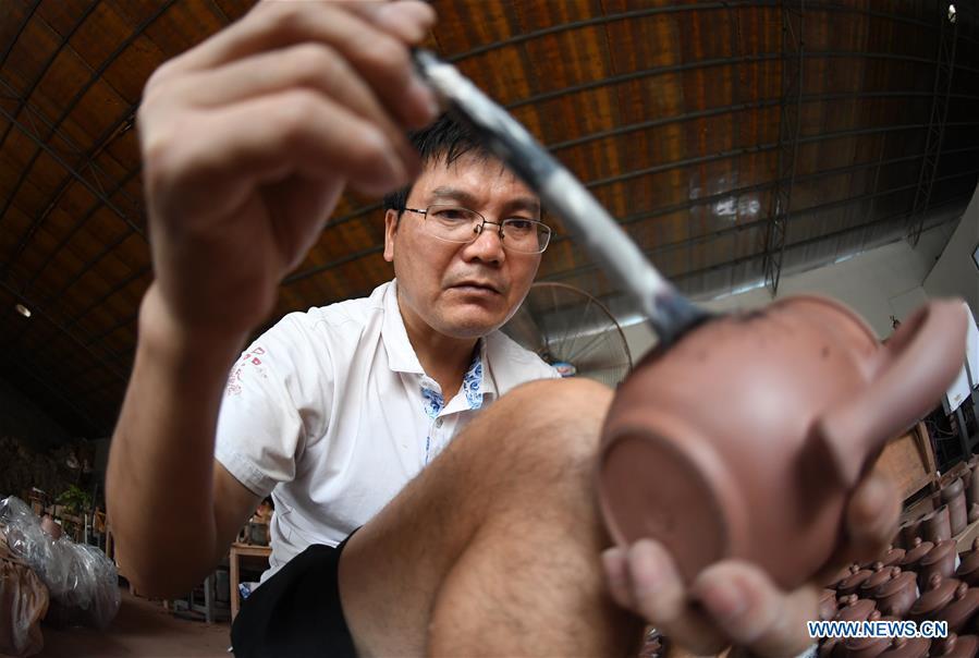 A staff member works on a Nixing pottery ware at a workshop in Qinzhou, south China\'s Guangxi Zhuang Autonomous Region, Oct. 9, 2018. The making of Nixing pottery is a well-preserved tradition in Qinzhou. In 2008, the techniques of making Nixing pottery were listed as one of China\'s state-level intangible cultural heritages. Currently, over 10,000 workers are engaged in the Nixing pottery industry in Qinzhou, producing more than 1,000 pottery varieties. (Xinhua/Lu Boan)