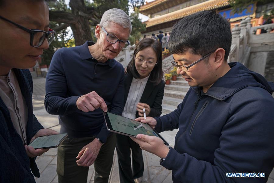 Liu Zhipeng (1st R), one of the founders of Xichuangzhu APP, shows Apple\'s CEO Tim Cook (2nd L) how to write calligraphy on iPad with Apple Pencil at Beijing Confucian Temple in Beijing, capital of China, on Oct. 10, 2018. Cook paid a visit to Beijing Confucian Temple and the Imperial College on Wednesday. (Xinhua/Cai Yang)