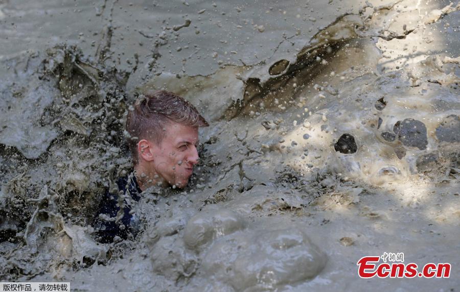 A competitor crosses a water obstacle during the \'Wild Boar Dirt Run\' (Wildsau Dirt Run) near Brand-Laaben, Austria, October 13, 2018. People took part in a hard obstacle course in three distances 5, 10 and 20 kilometers. (Photo/Agencies)