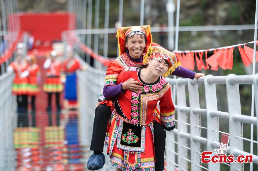 Women carrying their mothers-in-law on their back compete in a race on the 140-meter-long glass bridge in Jiulong River National Forest Park in Hunan Province, Oct. 16, 2018, ahead of the Double Nine Festival. Women from the She and Yao ethnic groups participated the competition. The 9th day of the 9th lunar month is the traditional Chongyang Festival, or Double Nine Festival, which falls on Oct. 17 this year. (Photo: China News Service/Yang Huafeng)