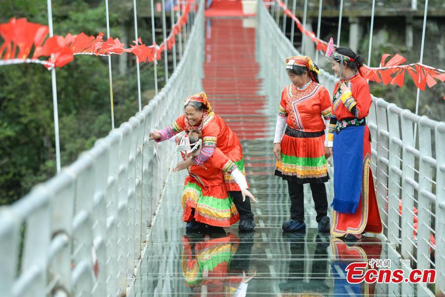 Women carrying their mothers-in-law on their back compete in a race on the 140-meter-long glass bridge in Jiulong River National Forest Park in Hunan Province, Oct. 16, 2018, ahead of the Double Nine Festival. Women from the She and Yao ethnic groups participated the competition. The 9th day of the 9th lunar month is the traditional Chongyang Festival, or Double Nine Festival, which falls on Oct. 17 this year. (Photo: China News Service/Yang Huafeng)