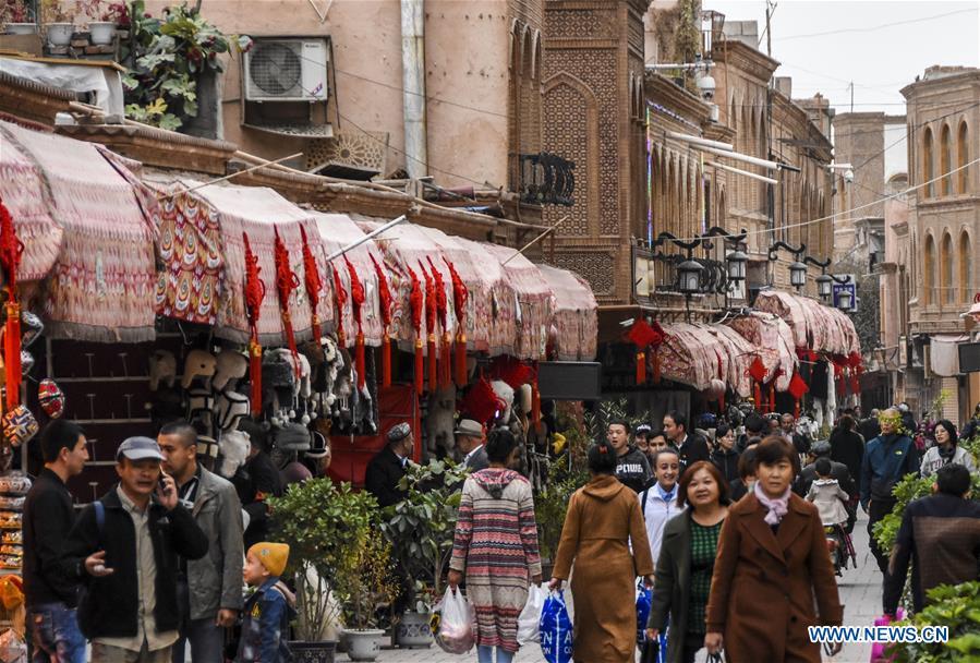 People walk on a shopping street in Kashgar City, northwest China\'s Xinjiang Uygur Autonomous Region, Oct. 16, 2018. The ancient oasis city of Kashgar, in the westernmost part of China near the border with Kyrgyzstan, Tajikistan, Afghanistan, and Pakistan, was an important staging post on the original Silk Road and has been revitalized as a bustling hub of business and different cultures. (Xinhua/Li Zhihao)