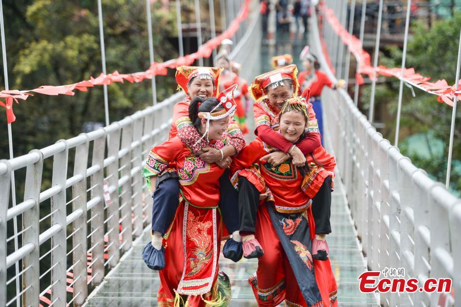 Women carrying their mothers-in-law on their back compete in a race on the 140-meter-long glass bridge in Jiulong River National Forest Park in Hunan Province, Oct. 16, 2018, ahead of the Double Nine Festival. Women from the She and Yao ethnic groups participated the competition. The 9th day of the 9th lunar month is the traditional Chongyang Festival, or Double Nine Festival, which falls on Oct. 17 this year. (Photo: China News Service/Yang Huafeng)
