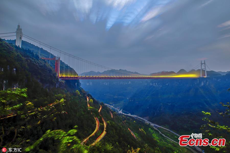 An early morning view of a winding road on a mountain and the Aizhai Bridge in Jishou City, Central China’s Hunan Province, Oct. 17, 2018. The suspension bridge was built as part of an expressway from southwest China\'s Chongqing Municipality to Changsha. The bridge links two tunnels 1,176 meters apart and carries traffic 330 meters above the floor of the Dehang Canyon, setting several records including the world\'s highest and longest tunnel-to-tunnel bridge. (Photo/IC)