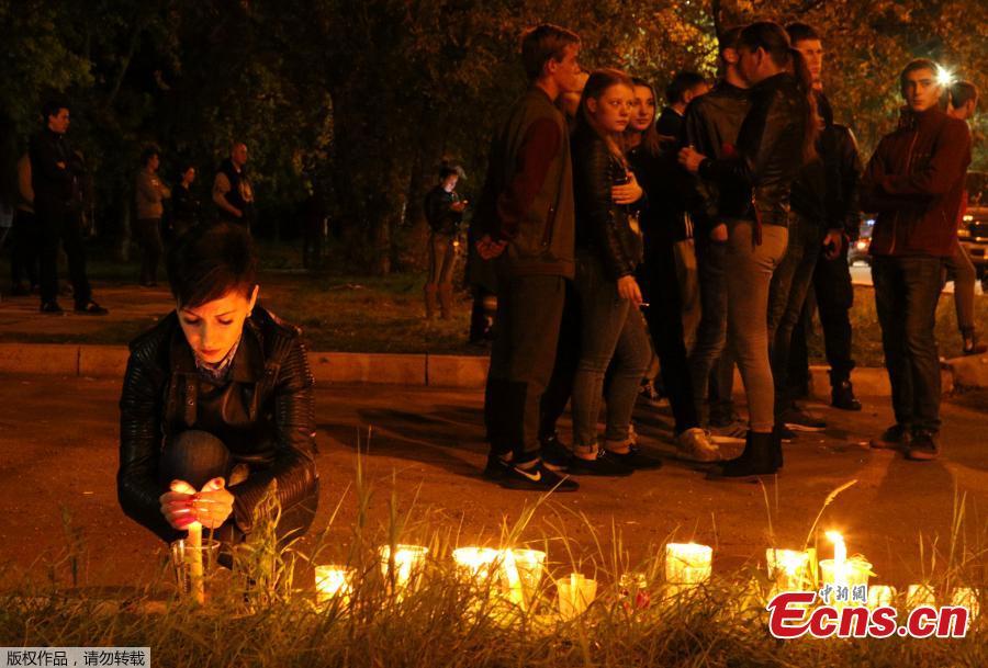 A woman lights a candle at a makeshift memorial near the scene of a fatal attack on a college in the port city of Kerch, Crimea, Oct. 17, 2018. At least 19 people have been killed and dozens injured in a mass shooting at the college. (Photo/Agencies)