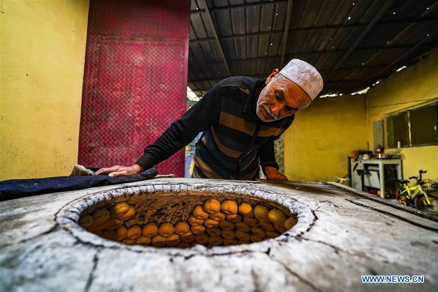 Yusup Tapuhan (C) makes butter naan at home in Yuli County of the Mongolian Autonomous Prefecture of Bayingolin, northwest China\'s Xinjiang Uygur Autonomous Region, Oct. 17, 2018. Yusup Tapuhan launched his butter naan business in 2000. The making of this popular pastry has been a tradition in Yuli County. In 2017, a dedicated local naan guild was established to help those in the business optimize profit. Yusup, who is 63, became one of the guild\'s earliest members. With the help of his family, Yusup can make 50 kilograms of butter naan and earn 500 yuan (72 U.S. dollars) a day. (Xinhua/Zhao Ge)