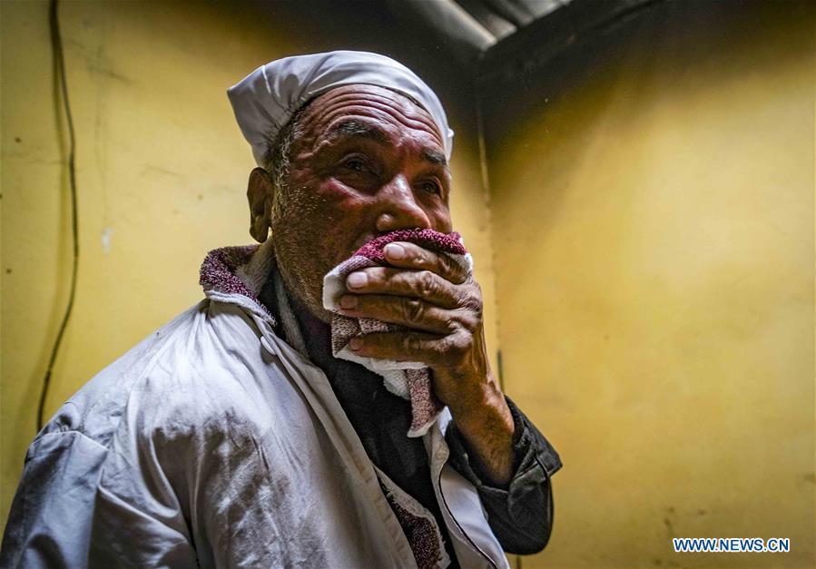 Yusup Tapuhan wipes sweat from his face while baking butter naan in Yuli County of the Mongolian Autonomous Prefecture of Bayingolin, northwest China\'s Xinjiang Uygur Autonomous Region, Oct. 17, 2018. Yusup Tapuhan launched his butter naan business in 2000. The making of this popular pastry has been a tradition in Yuli County. In 2017, a dedicated local naan guild was established to help those in the business optimize profit. Yusup, who is 63, became one of the guild\'s earliest members. With the help of his family, Yusup can make 50 kilograms of butter naan and earn 500 yuan (72 U.S. dollars) a day. (Xinhua/Zhao Ge)