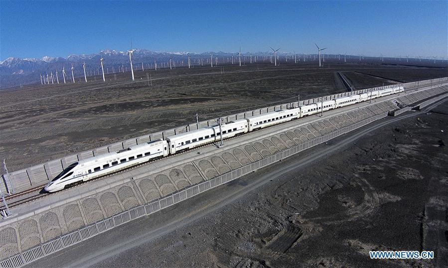 A bullet train runs past a wind power plant in Urumqi, northwest China\'s Xinjiang Uygur Autonomous Region, Nov. 16, 2014. Xinjiang has seen a surge in the electricity generation from clean energy. According to State Grid Xinjiang Electric Power Co., Ltd., wind and solar power generated 27.81 billion and 9.07 billion kilowatt hours (kwh) of electricity, respectively, in the first nine months of 2018 in the region. With abundant wind and solar resources, Xinjiang is a pioneer in using new energy in China, with installed new-energy capacity having exceeded 27 million kilowatts so far. (Xinhua/Jiang Wenyao)