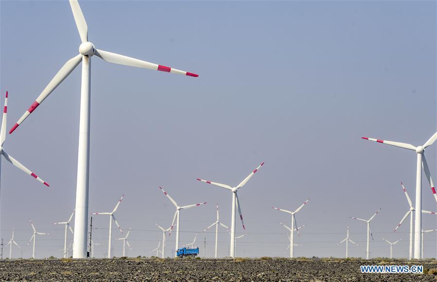 A vehicle runs across a wind power plant in Urumqi, northwest China\'s Xinjiang Uygur Autonomous Region, Sept. 18, 2018. Xinjiang has seen a surge in the electricity generation from clean energy. According to State Grid Xinjiang Electric Power Co., Ltd., wind and solar power generated 27.81 billion and 9.07 billion kilowatt hours (kwh) of electricity, respectively, in the first nine months of 2018 in the region. With abundant wind and solar resources, Xinjiang is a pioneer in using new energy in China, with installed new-energy capacity having exceeded 27 million kilowatts so far. (Xinhua/Zhao Ge)