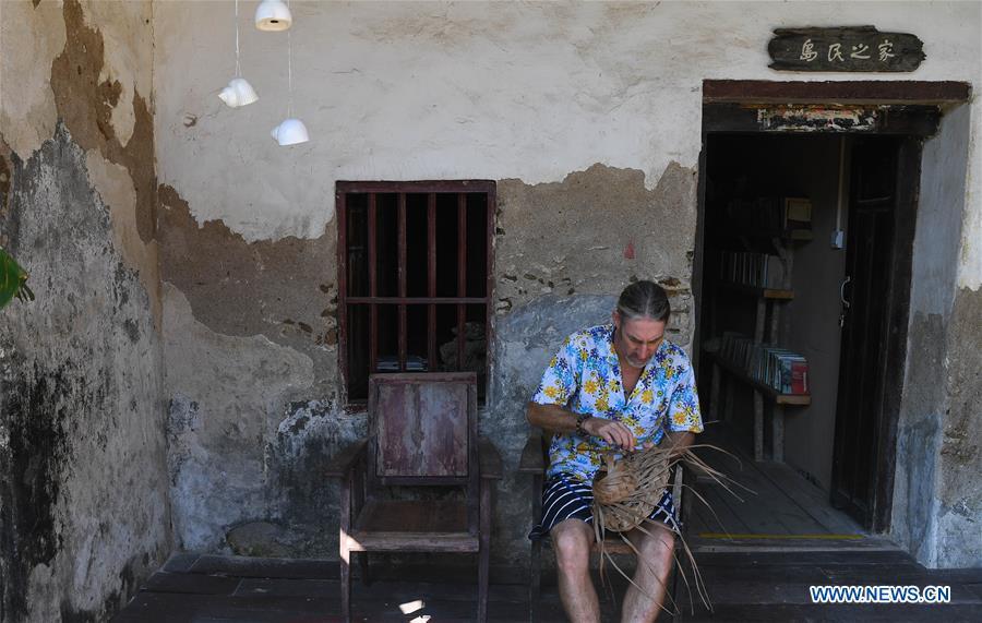 Canadian Craig Anderson makes artwork on the West Island in Sanya, south China\'s Hainan Province, Sept. 20, 2018. Anderson arrived in February at the West Island inhabited by around 4,000 people. Locals regarded Anderson as a scavenger when he first arrived, as he wandered around the beach almost every day, picking up driftwood, plastic bottles, shattered glasses, and rusty pieces of iron. As time went by, the locals realized that Anderson is an artist who devotes himself in environment protection art design. He profits the recyclable and regenerative materials in making art works. (Xinhua/Yang Guanyu)