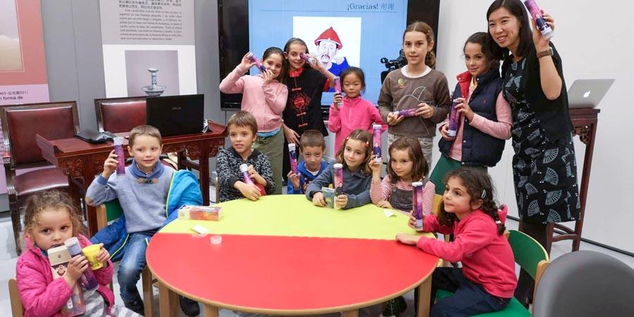 Children take photos with handcrafts they made at the China Cultural Center in Madrid, Oct 20, 2018. (Photo/Chinaculture.org)