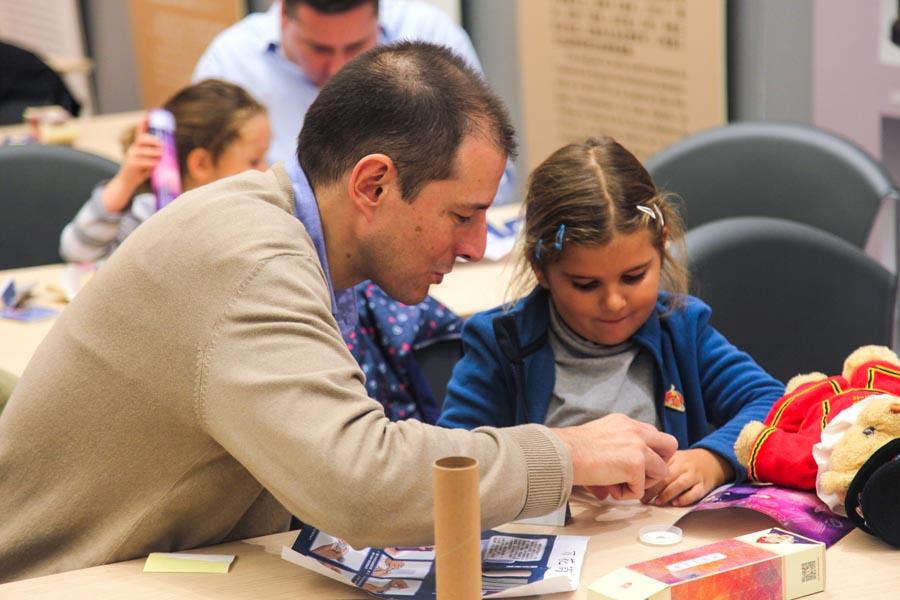 A man accompanies his daughter to make handcrafts at the China Cultural Center in Madrid on Oct 20, 2018. During the workshop, people learnt different aspects of the Qing Dynasty culture including royal clothes and traditional Chinese architecture.(Photo/Chinaculture.org)