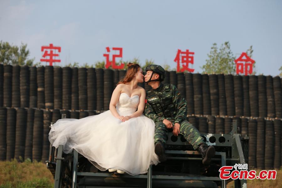 An armed police squad head in Yantai City, East China’s Shandong Province and his wife took special wedding photos at a barrack amid cheers and support of other members of the paramilitary police unit. (Photo: China News Service/Yang Lei)