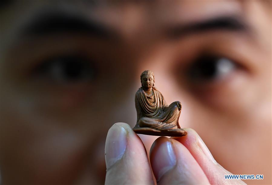 Lin Jianjun shows his wood carving at a studio in Putian, southeast China\'s Fujian Province, Oct. 23, 2018. Lin Jianjun, who learnt wood carving at the age of 16, has studied the making skill of this traditional artwork for more than 20 years. In 2014, Lin got married with Chen Qin. The wife was influenced by her husband and got interested in wood carving. She developed the wood carving by combining a traditional skill to make wood carving inlaid with gold and silver. The couple meanwhile try to promote the Putian wood carving by giving lessons, instructing apprentices and displaying their works to the public. In 2018, Lin was appointed as the inheritor of the wood carving skill, a provincial-level intangible cultural heritage.(Xinhua/Zhang Guojun)