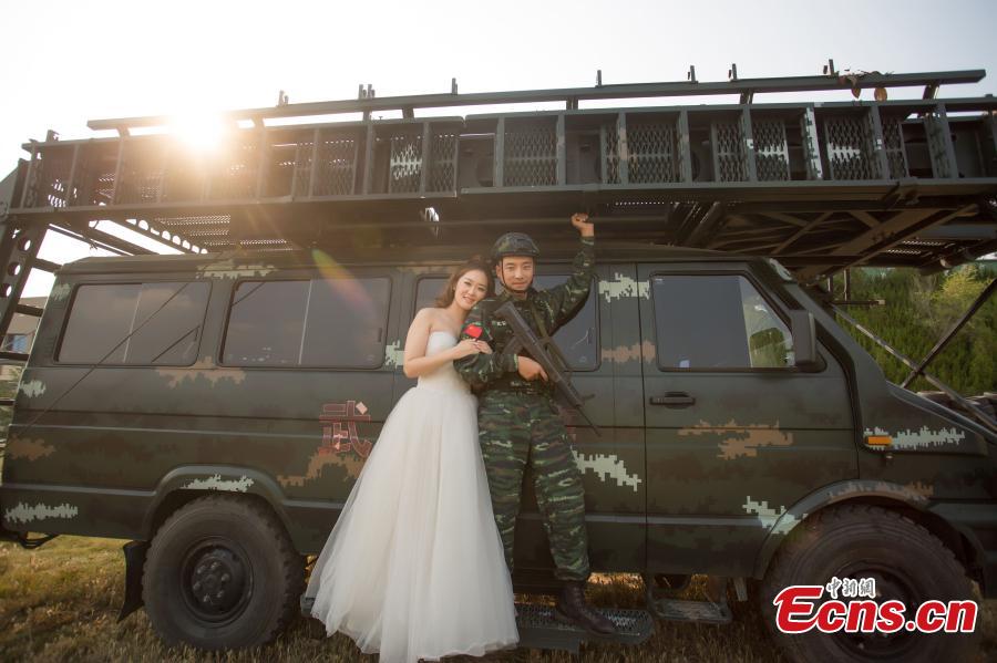 An armed police squad head in Yantai City, East China’s Shandong Province and his wife took special wedding photos at a barrack amid cheers and support of other members of the paramilitary police unit. (Photo: China News Service/Yang Lei)