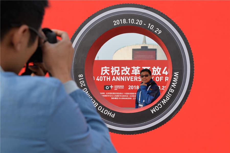 A visitor poses for a photo during Photo Beijing 2018 at the China Millennium Monument in Beijing, Oct. 20, 2018. (Photo/Xinhua)
The Photo Beijing 2018 event is ongoing at the China Millennium Monument in Beijing and includes 66 exhibitions, one forum, 32 lectures and more than 10 promotional activities. During the exhibitions, a total of 3,047 photographs and 52 video works created by artists from 31 countries are on show and free to view. The exhibition will last until Oct. 29.
Besides the main venue at the China Millennium Monument, the event also goes out to local communities, schools and art spaces, and sets up parallel venues.
During a parallel venue at the Jianguomen community, more than 30 award-winning photographs on display reflect local cultural heritage, achievements in community management, and changes of living environments over the past years.