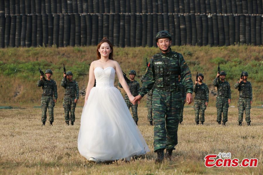 An armed police squad head in Yantai City, East China’s Shandong Province and his wife took special wedding photos at a barrack amid cheers and support of other members of the paramilitary police unit. (Photo: China News Service/Yang Lei)