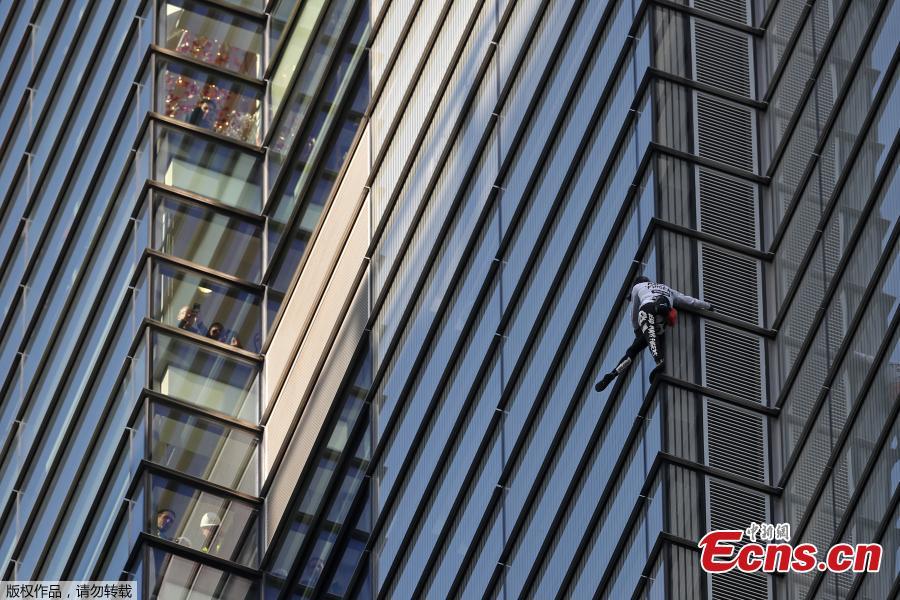 People (L) look out of nearby windows as French urban climber Alain Robert, also known as \