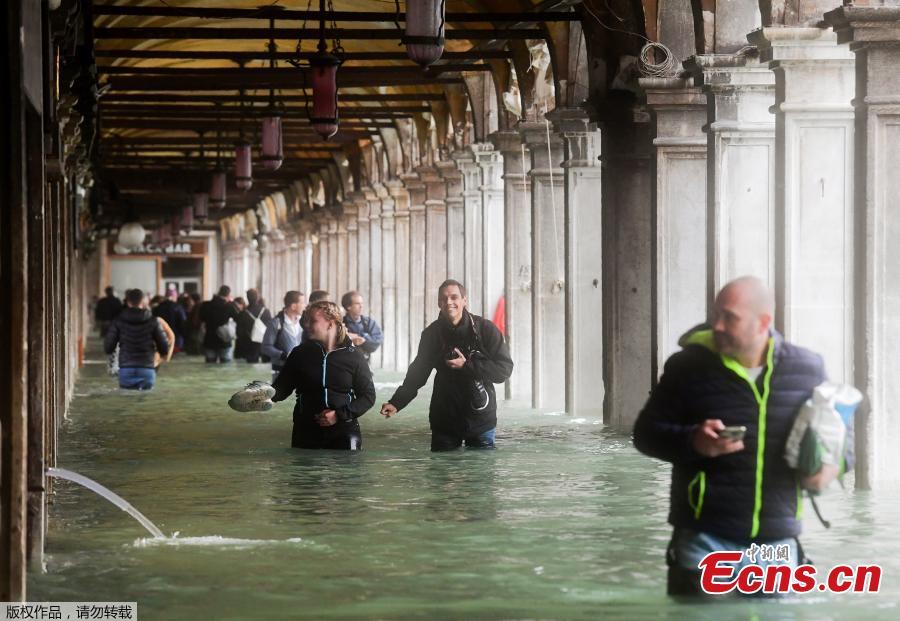 Tourists under arches next to the flooded St Mark\'s Square during a high-water alert in Venice on October 29, 2018. The flooding, caused by a convergence of high tides and a strong Sirocco wind, reached around 150 centimetres on October 29, 2018. (Photo/Agencies)
