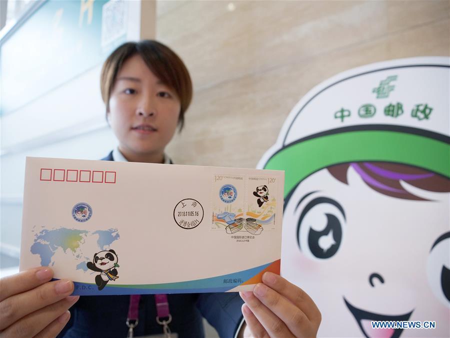 A staff member shows the first day cover with stamps released to commemorate the China International Import Expo (CIIE) at the National Exhibition and Convention Center in Shanghai, east China, Nov. 5, 2018.(Xinhua/Wang Yiliang)