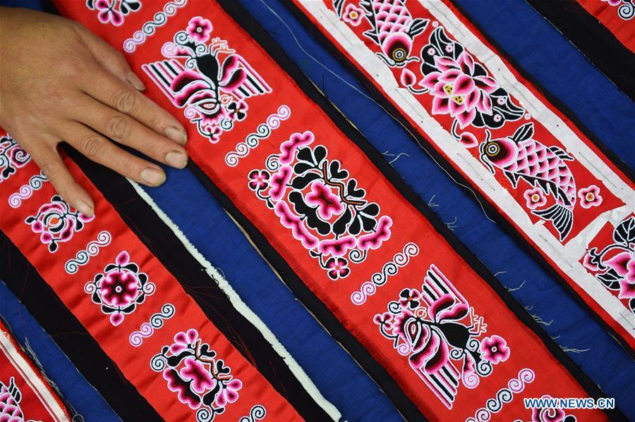 Yang Xinghe shows embroidered decorations for Miao costumes at Xinjiang Village in Taijiang County of Qiandongnan Miao and Dong Autonomous Prefecture, southwest China\'s Guizhou Province, on Nov. 4, 2018. Born with hearing loss, Yang Xinghe, 28, is a female of the Miao ethnic group, who are engaged in Miao embroidery at the village. She learned embroidery from her mother when she was only a child, and has been a locally well-known master now. (Xinhua/Liu Kaifu)