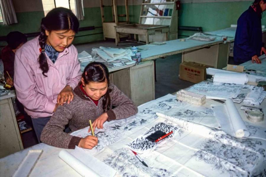 Sun Yuzhen watches as her colleague draws a sketch of a carpet. (Photo by Jamie Fouss/provided to chinadaily.com.cn)