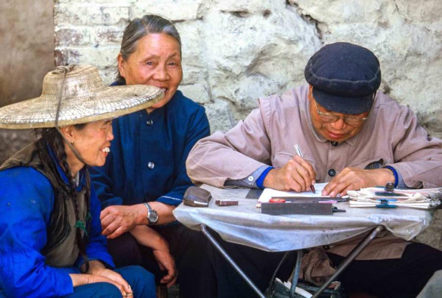 A man was helping the women to write a letter in Dali, Southwest China\'s Yunnan province. Dali was just opened to tourists two weeks before we arrived. We had to get special permission to go, so people there were very surprised to see us. It was a small town. In the hotel, there were crowds of people who wanted to talk to us to practice their English. (Photo by Jamie Fouss/provided to chinadaily.com.cn)