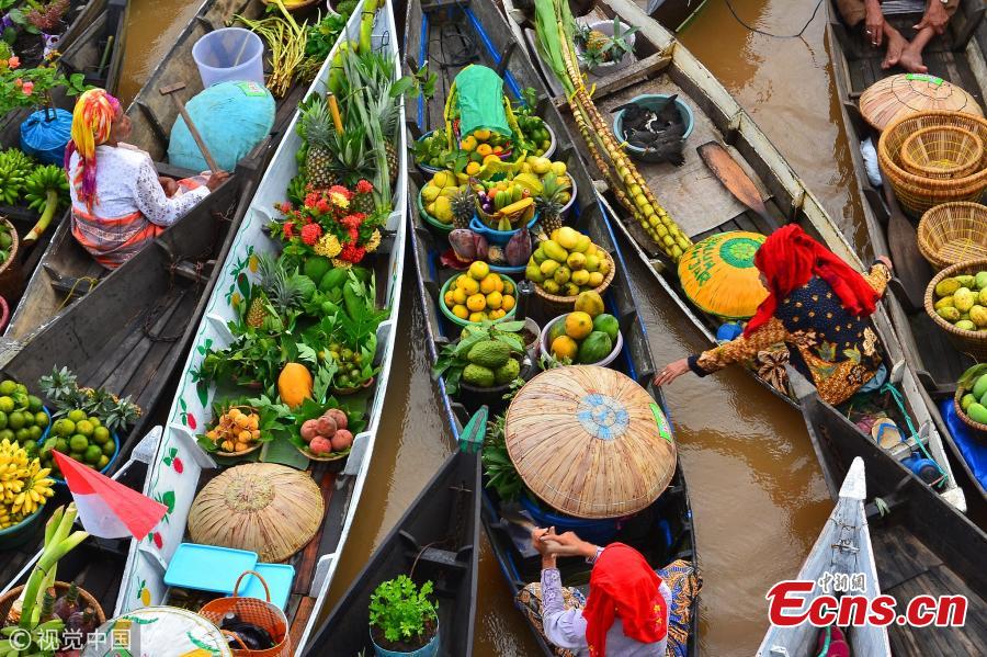 Hundreds of colorful boats tightly cram together at the Lok Baintan Floating Market to sell their hand-picked exotic fruit and vegetable in the Banjar district of Indonesia. The Lok Baintan floating market is in Southern Kalimantan Island dates back more than 500 years. Local people rely heavily on the waterways to make a living, with the markets now becoming tourist attractions. (Photo/VCG)