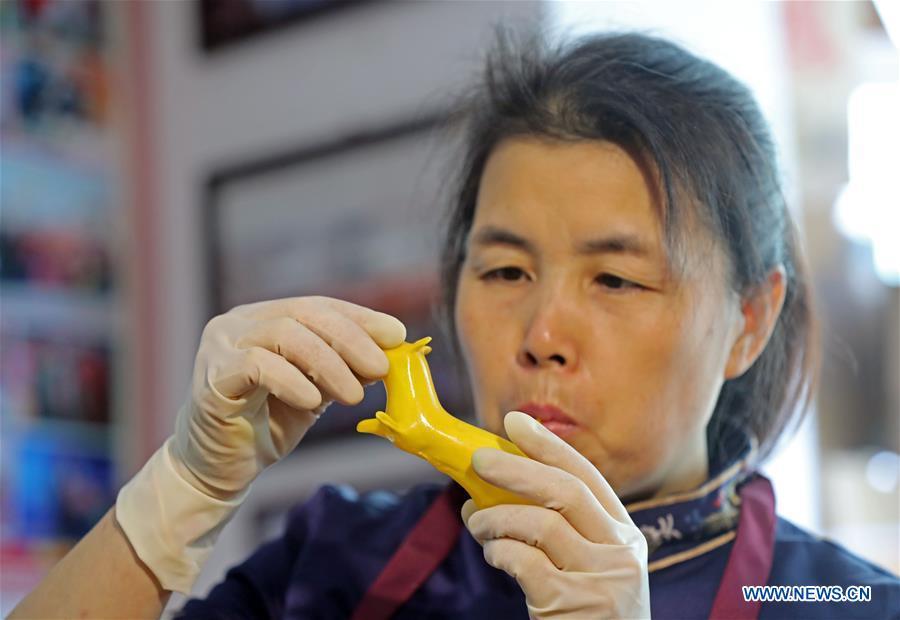 Folk artist Li Fengyan works on a sugar sculpture in Shenyang, northeast China\'s Liaoning Province, Nov. 6, 2018. The sugar sculpture of the Li family was listed as an intangible cultural heritage by the city of Shenyang. As the fifth-generation inheritor of her family\'s craft, Li Fengyan is making efforts to pass down the set of sugar-sculpting know-hows to her apprentices. (Xinhua/Yang Qing)