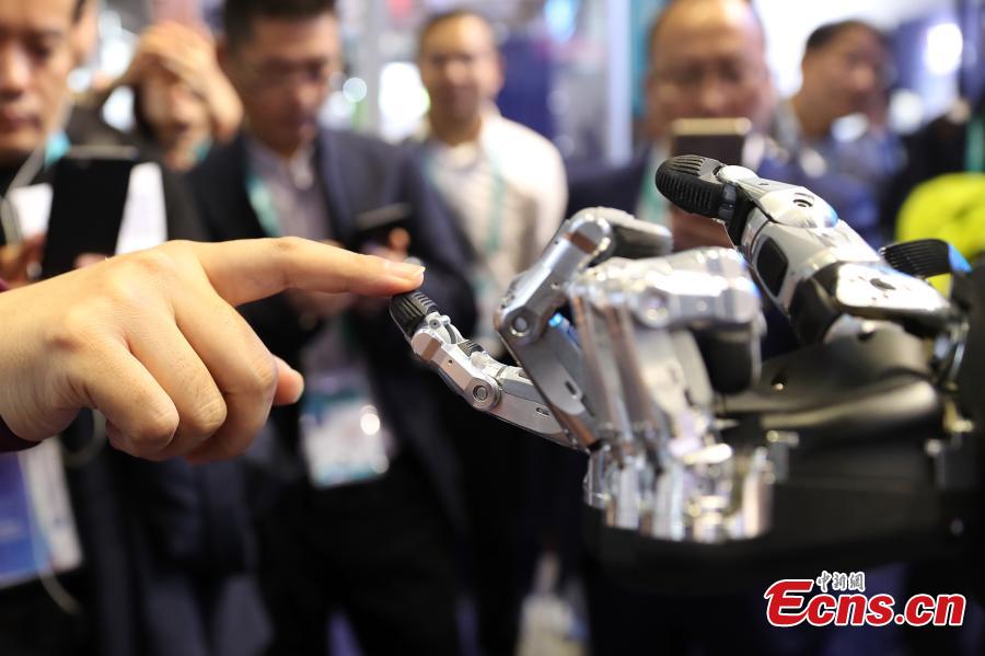 Visitors are attracted by a robotic hand shown at the first China International Import Expo (CIIE) in Shanghai, east China, Nov. 7 2018. The SCHUNK SVH 5-finger gripping hand is amazingly similar to the human model in terms of size, shape and agility. Nine drives enable the robotic hand to carry out gripping operations like holding a needle. (Photo: China News Service/Zhang Hengwei)
