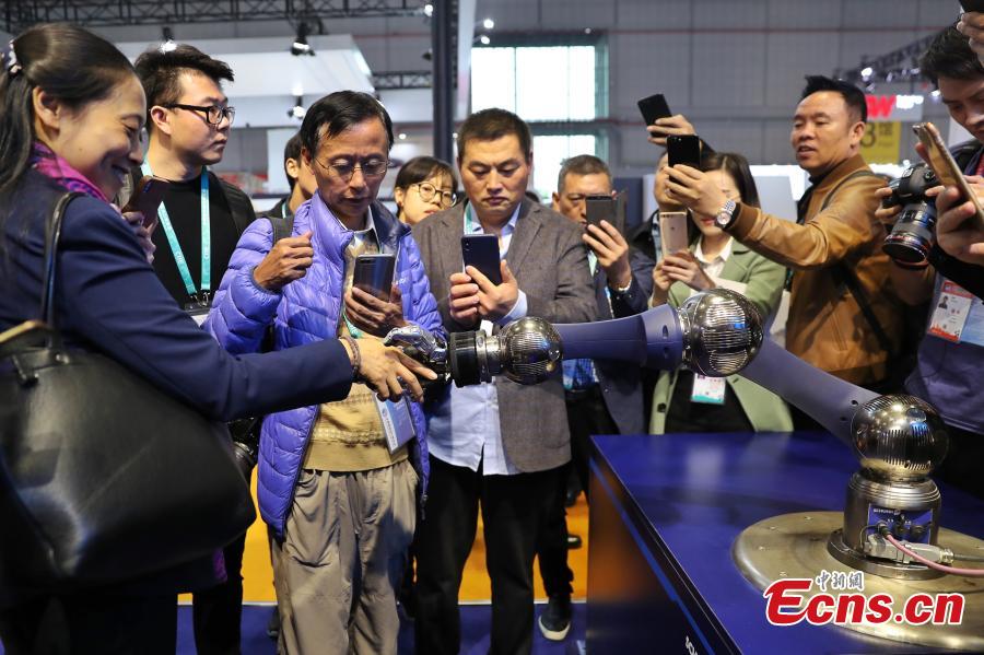 Visitors are attracted by a robotic hand shown at the first China International Import Expo (CIIE) in Shanghai, east China, Nov. 7 2018. The SCHUNK SVH 5-finger gripping hand is amazingly similar to the human model in terms of size, shape and agility. Nine drives enable the robotic hand to carry out gripping operations like holding a needle. (Photo: China News Service/Zhang Hengwei)