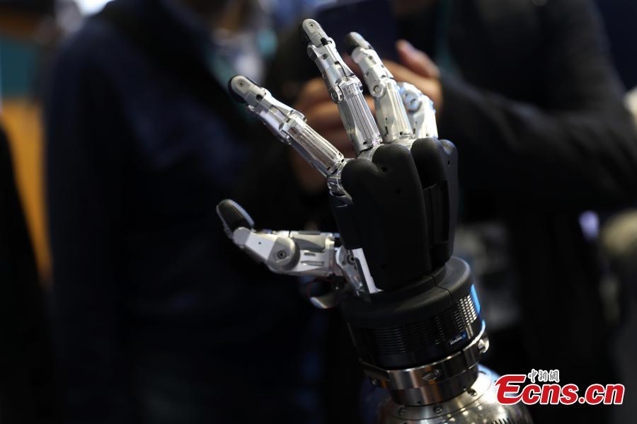 Visitors are attracted by a robotic hand shown at the first China International Import Expo (CIIE) in Shanghai, east China, Nov. 7 2018. The SCHUNK SVH 5-finger gripping hand is amazingly similar to the human model in terms of size, shape and agility. Nine drives enable the robotic hand to carry out gripping operations like holding a needle. (Photo: China News Service/Zhang Hengwei)