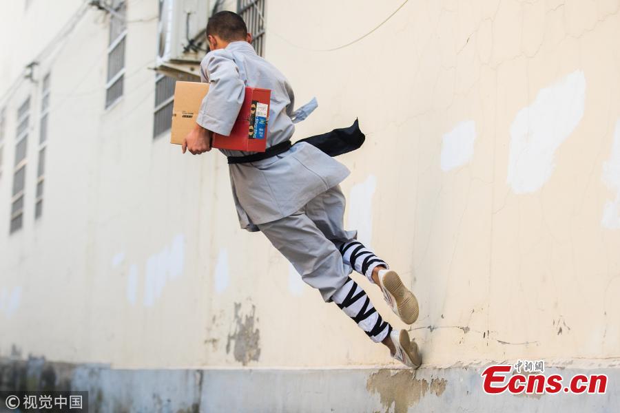 Wearing monk\'s robes, two Kung fu masters do a part time job as delivery man in Dengfeng city, Central China’s Henan province. With their special stunts of martial arts, the two can give a hand to local couriers in preparation for the approaching annual Singles Day online shopping extravaganza on November 11. (Photo/VCG)