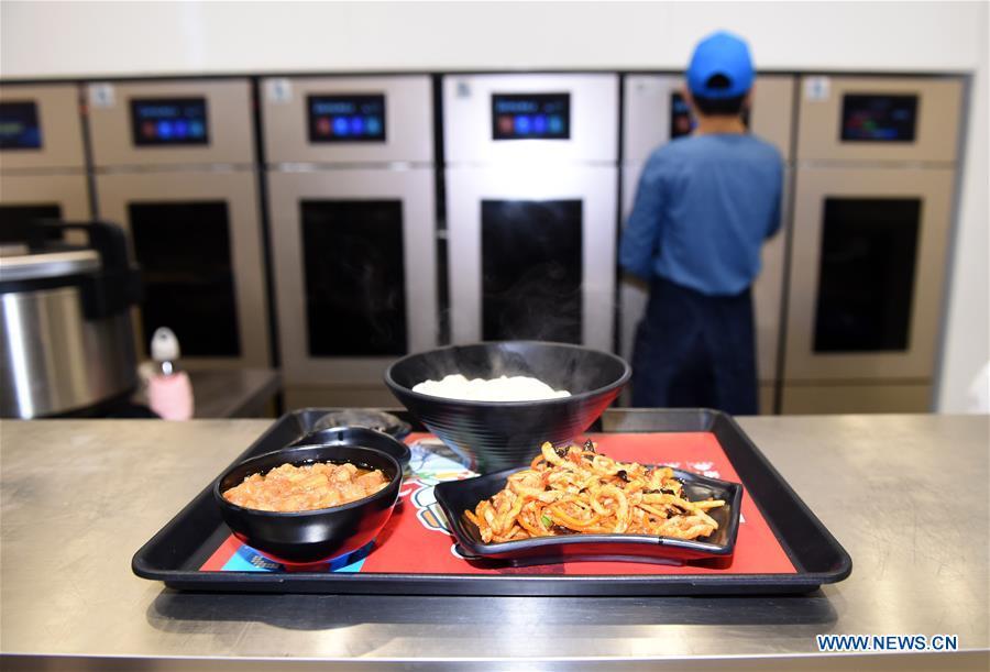 A worker operates a cooking machine in a cookless restaurant in central Beijing, capital of China, Nov. 7, 2018. The restaurant, equipped with 7 cooking machines that are programmed to prepare some popular Chinese dishes in minutes without human interference. Working along with smart payment and raw material supply systems, the cooking machine provides instant and standardized dishes. (Xinhua/Luo Xiaoguang)