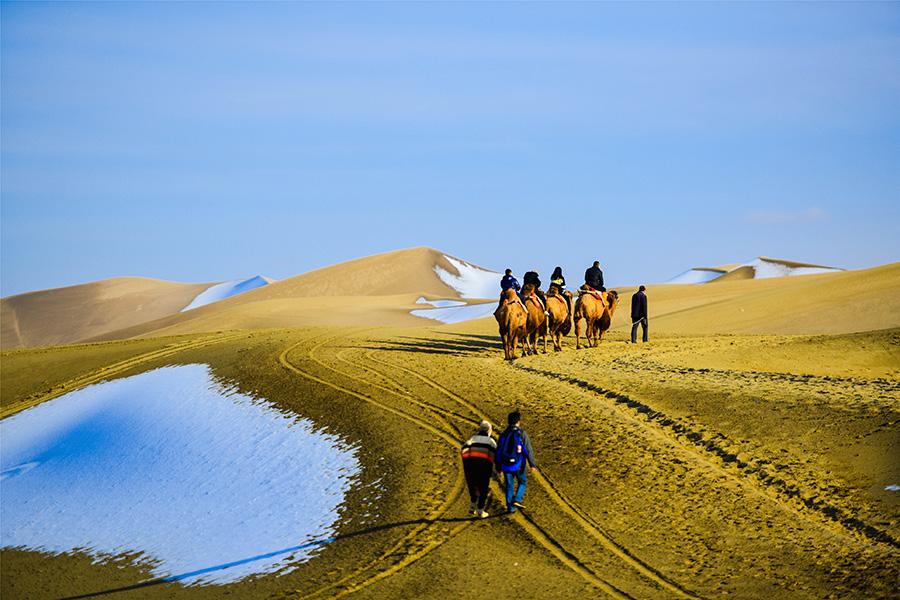 Dunhuang embraces this winter\'s first snowfall on Nov. 14. As the sun comes out, snow scenery in local landmark attractions like the Mingsha Mountain and Yueya Spring, a crescent-shaped spring-fed lake surrounded by desert, turns to a fairyland. (Photo/China Daily)