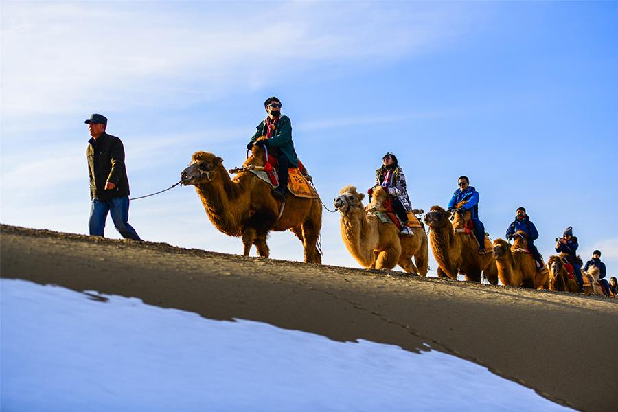 Dunhuang embraces this winter\'s first snowfall on Nov. 14. As the sun comes out, snow scenery in local landmark attractions like the Mingsha Mountain and Yueya Spring, a crescent-shaped spring-fed lake surrounded by desert, turns to a fairyland. (Photo/China Daily)