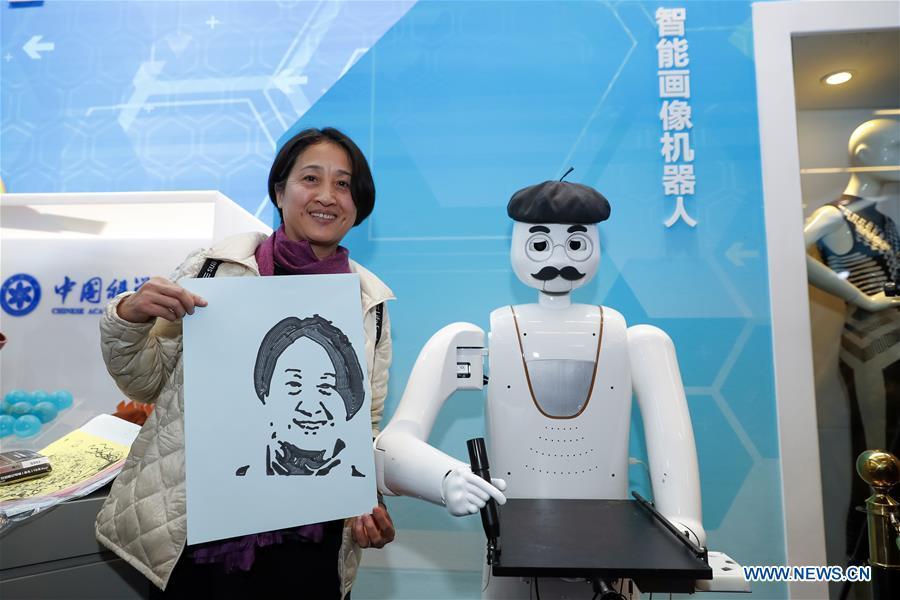 A visitor shows a portrait drawn by an intelligent painting robot with facial recognition function during a major exhibition to commemorate the 40th anniversary of China\'s reform and opening-up at the National Museum of China in Beijing, capital of China, Nov. 20, 2018. It can finish a portrait within three to five minutes. (Xinhua/Shen Bohan)
