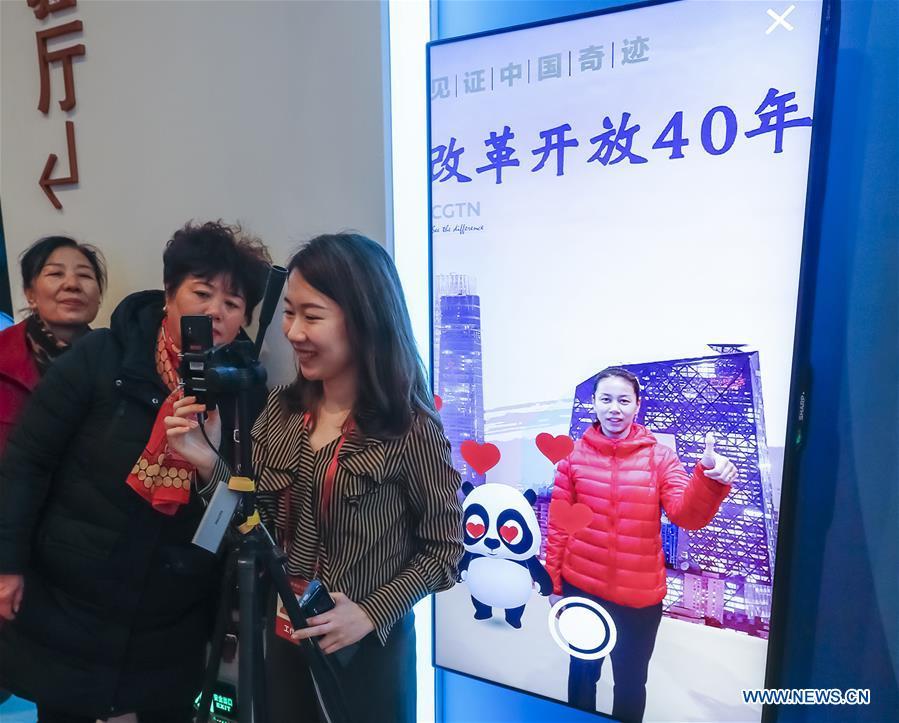 Visitors interact with a virtual panda of augmented reality (AR) experience project and pose for photo during a major exhibition to commemorate the 40th anniversary of China\'s reform and opening-up at the National Museum of China in Beijing, capital of China, Nov. 20, 2018. (Xinhua/Shen Bohan)
