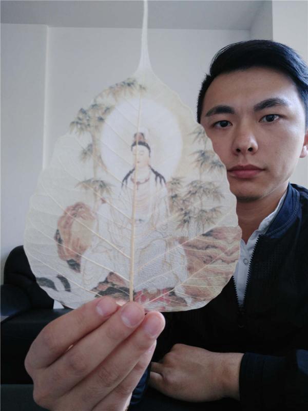 Ding Li takes a selfie with his artwork in his workshop in Xianning city, Hubei Province. (Photo provided to chinadaily.com.cn)
Leaf painting has a history of more than 2,000 years in China. A 27-year-old man Ding Li, from Xianning city of Hubei Province has devoted a dozen years to learning leaf art, and fuses ancient tattooing techniques into his creations. Ding has spent one year creating the ancient painting Along the River During the Qingming Festival which is painted on 10 pieces of michelia alba leaves.
Ding started to learn painting at 5, and began learning carving at 12. When he first found out about leaf painting at 13 years old, he became obsessed with the art.
The process of making leaf paintings is quite complicated. First the artist selects fine linden leaves or michelia alba leaves from mountains in Yunnan province, then go through over 60 steps such as cutting, soaking, pressing, sculpting, grinding, ironing and bleaching. The whole affair takes at least two to three months to finish.
Two of Ding\'s works won the silver award during a recent art exhibition between China and Japan on Oct. 28.
Before each creation, Ding will first learn related historical stories to make his artwork more detailed. \
