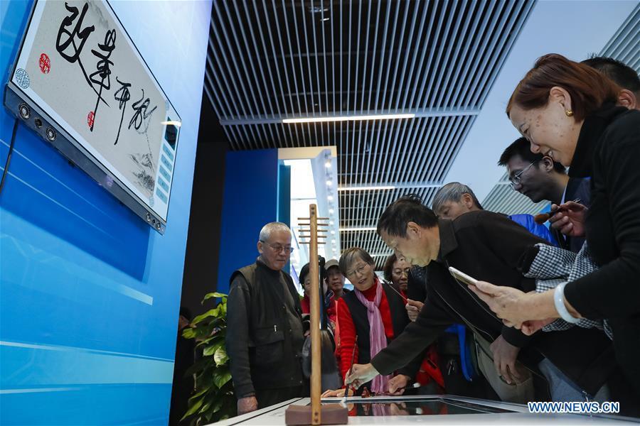 The 64-year-old Huang Chengchu from central China\'s Hunan Province experience an intelligent calligraphy exhibit during a major exhibition to commemorate the 40th anniversary of China\'s reform and opening-up at the National Museum of China in Beijing, capital of China, Nov. 20, 2018. (Xinhua/Shen Bohan)