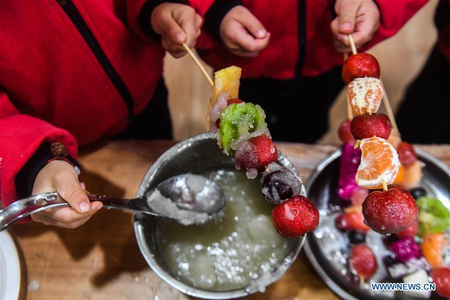 Children use orange, hawthorn and other fruits to make a kind of traditional food during an activity held at a kindergarten in Lijiaxiang Township of Changxing County, east China\'s Zhejiang Province, Nov. 21, 2018. The activity was held to greet the light snow, one of the 24 solar terms of the Chinese lunar calendar. (Xinhua/Xu Yu)