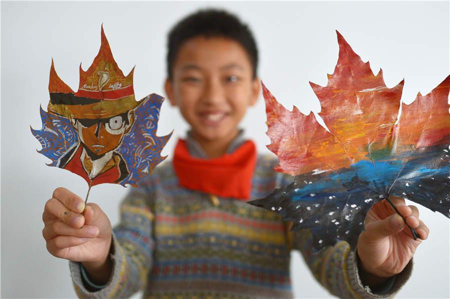 A student shows his leaf art at a primary school in Qingdao, East China\'s Shandong Province, on Nov. 19, 2018. (Photo/Asianewsphoto)
Students from a primary school in Qingdao city, Shandong Province have created leaf art through drawing and carving. Liu Ping, an art teacher at the school who is enthusiastic about the style, provides guidance to students during the process.