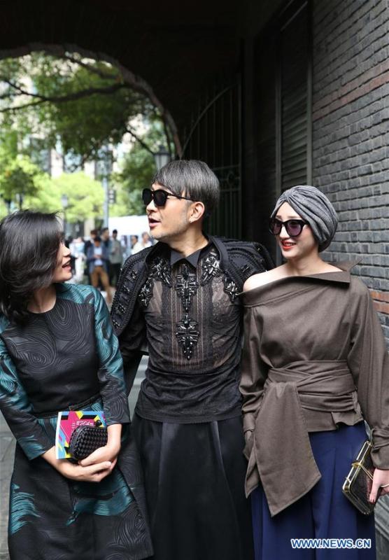 File photo taken on April 11, 2016 shows people wearing fashionable costumes outside the venue of a fashion show in east China\'s Shanghai. From 1978 when China started its reform and opening-up policy, a door to the outside world has been opened. Along with the imported commodities, fashion ideas inevitably slipped into China and since then the country, which was somewhat lack of fashion diversity, started its journey to pursue fashions. Over the past four decades, the thirst for beauty has driven Chinese people to pursue every possible fashionable element. The change first came with dress when colorful and diversified clothing prevailed as against the former dominant blue and grey. For a time, men and women raced to hairdressers\' just for trendy hairdos. Eating McDonald\'s or western cuisine even once was regarded as a fashionable thing. However, the most conspicuous change is that Chinese people have become more inclusive and they tend to accept new fashions, styles and concepts. China nowadays is dazzling the world not only on the fashion stage but in many other fields. Changes in fashions, as a profile of society, has well interpreted the benefits to people brought by China\'s reform and opening-up policy. (Xinhua/Ren Long)